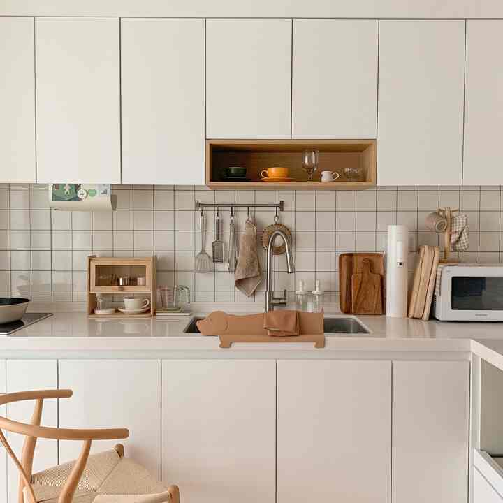 A clean kitchen space featuring white and wood tones with a dog-shaped kitchen towel holder prominently displayed.