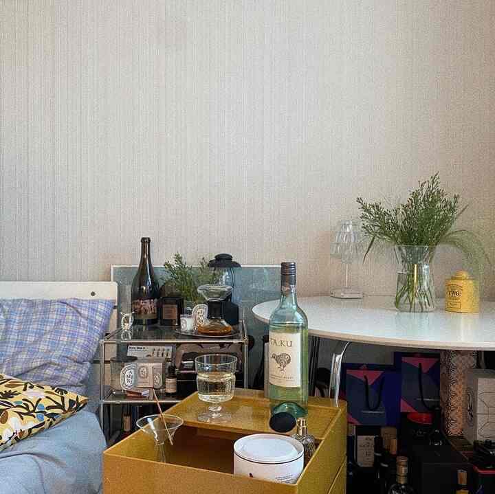 A modern and cozy bedroom featuring white and yellow tones, with a nightstand and a round dining table