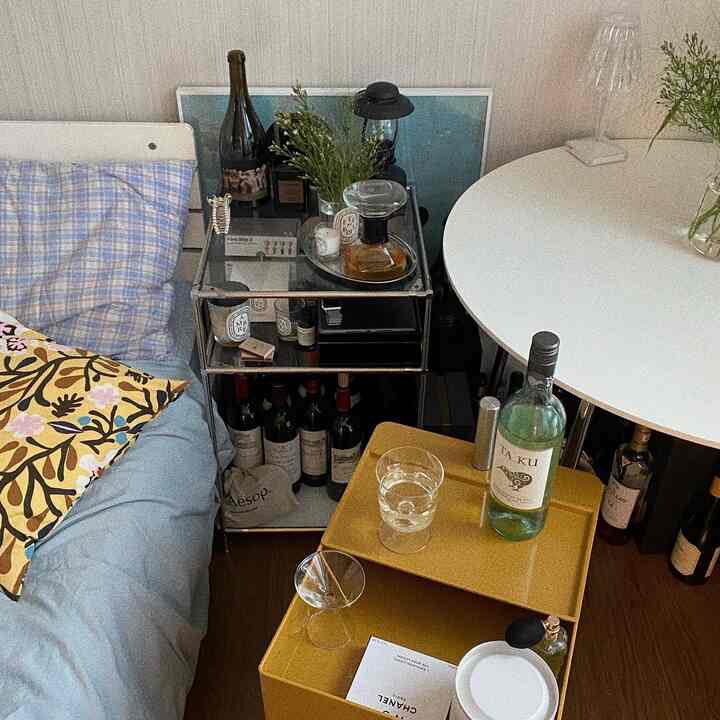 White and yellow toned bedroom space featuring bed, side tables, and wine glassware, creating a cozy home bar atmosphere