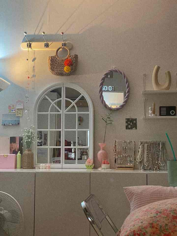 ホワイトとナチュラルの色調のワンルーム、壁にアーチ型の鏡と様々なインテリア小物が配置された雰囲気のある空間