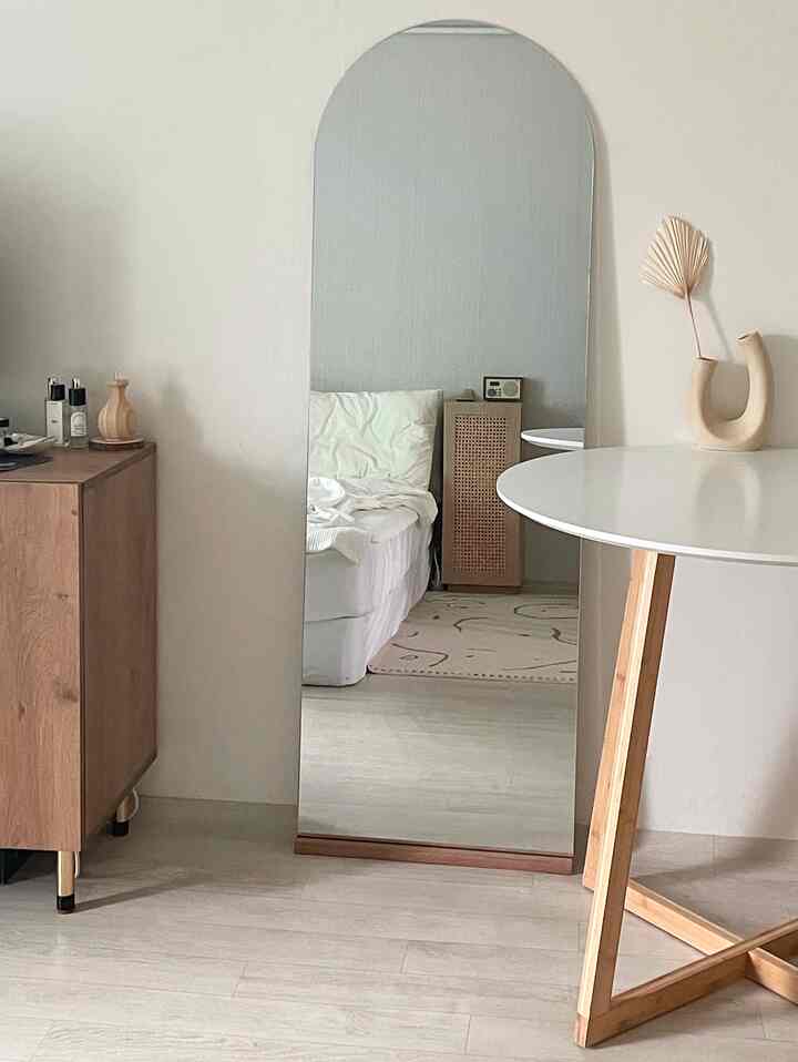 Natural minimal living room featuring a large white and wood tone mirror with simple wooden furniture pieces