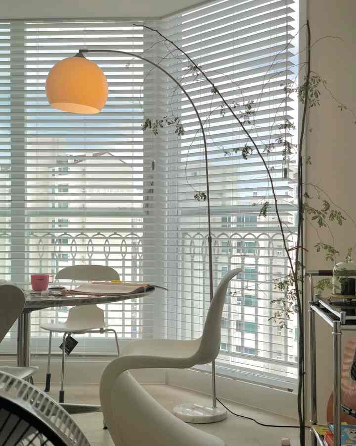 Bright white-toned dining room featuring Mid-Century Modern dining chairs and a floor lamp creating a modern atmosphere