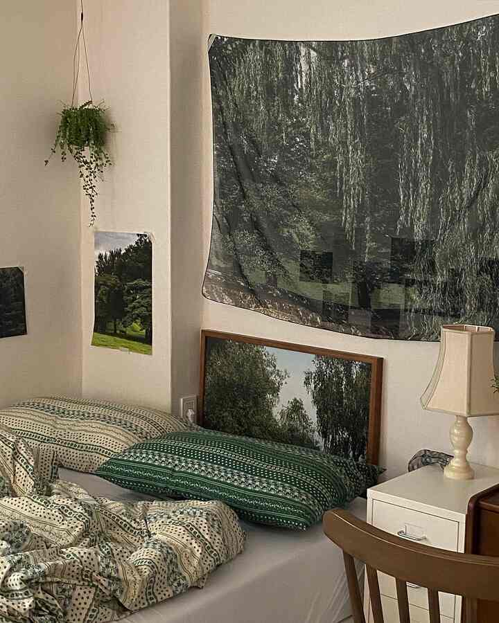 グリーンとホワイトのトーンが調和した寝室、ヴィンテージ柄の寝具と植物が配置された雰囲気のあるインテリア