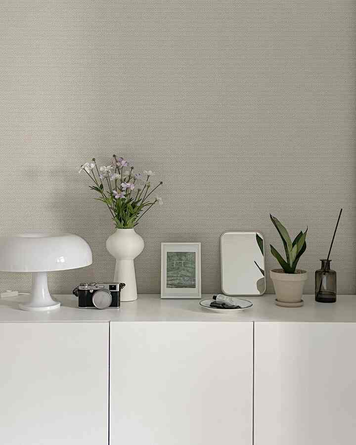 落ち着いたベージュ色の壁とホワイトのキャビネットが配置されたシンプルでナチュラルなオブジェのあるインテリア