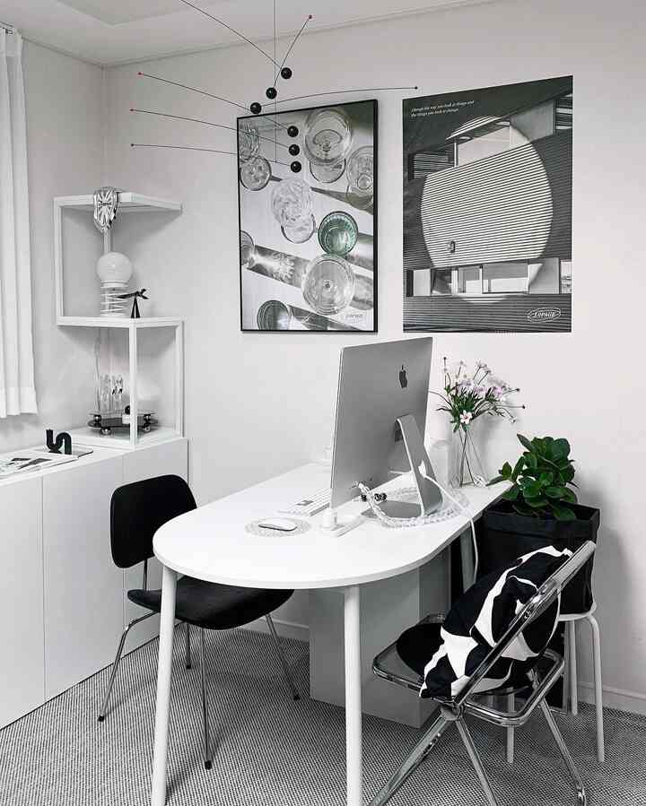 Modern white home office featuring a white desk, black office chair, and wall art in a clean workspace