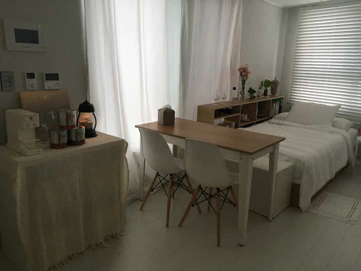 白と木目調の寝室兼ダイニング、シンプルでナチュラルな雰囲気のインテリア