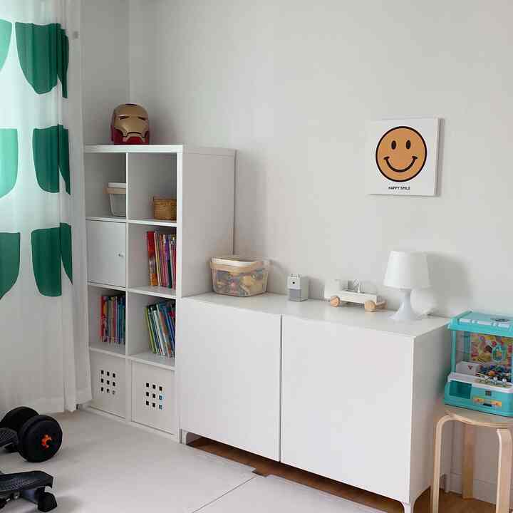 White and green toned kids' room featuring bookshelf, storage cabinet, and organized toys with a tidy atmosphere