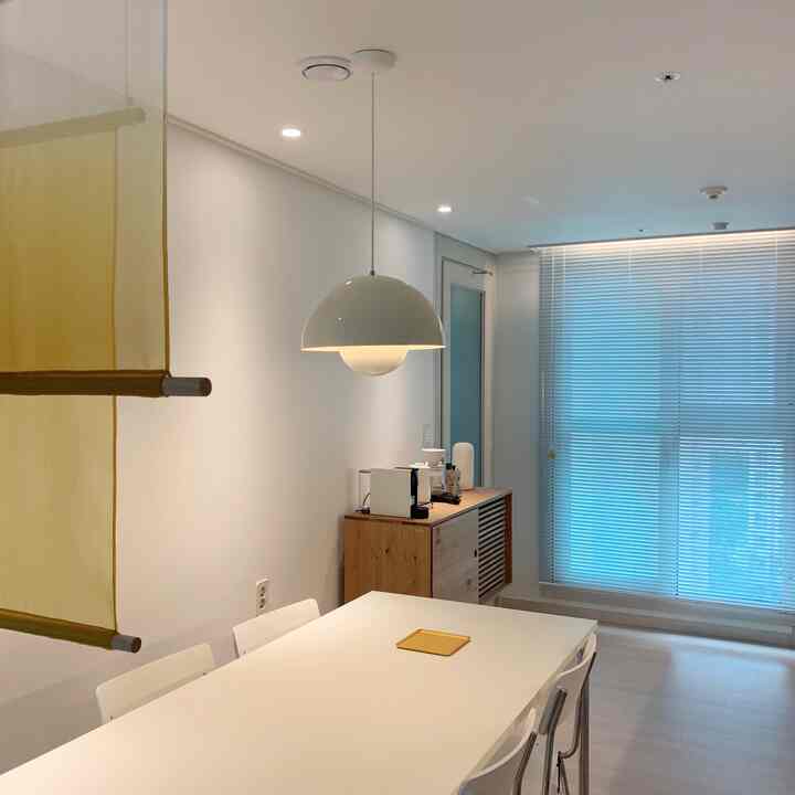 Clean kitchen and dining room with white and natural tones, featuring blinds and pendant lighting creating a cozy atmosphere