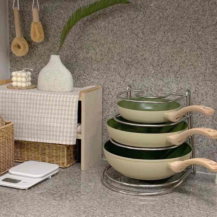 Gray stone kitchen area featuring natural brown baskets and neatly stacked frying pans with wooden handles