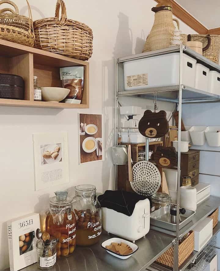 ホワイトと木目調が調和したキッチン収納スペース、ラタンバスケットときれいに整理された食器や器具が配置されたナチュラルなインテリア