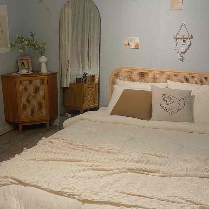 ベージュと木目調の寝室、アーチ型ミラーとラタン製コーナーキャビネットが配置された雰囲気のあるインテリア