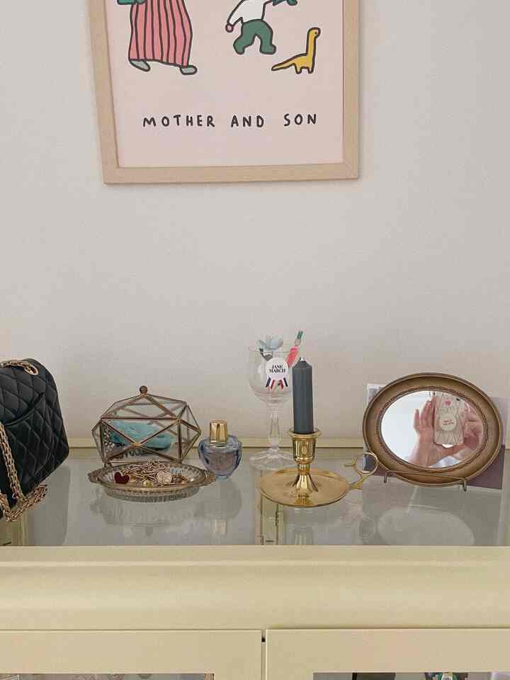 アイボリー色のキャビネットの上に様々な装飾品とポスターが配置された落ち着いた空間