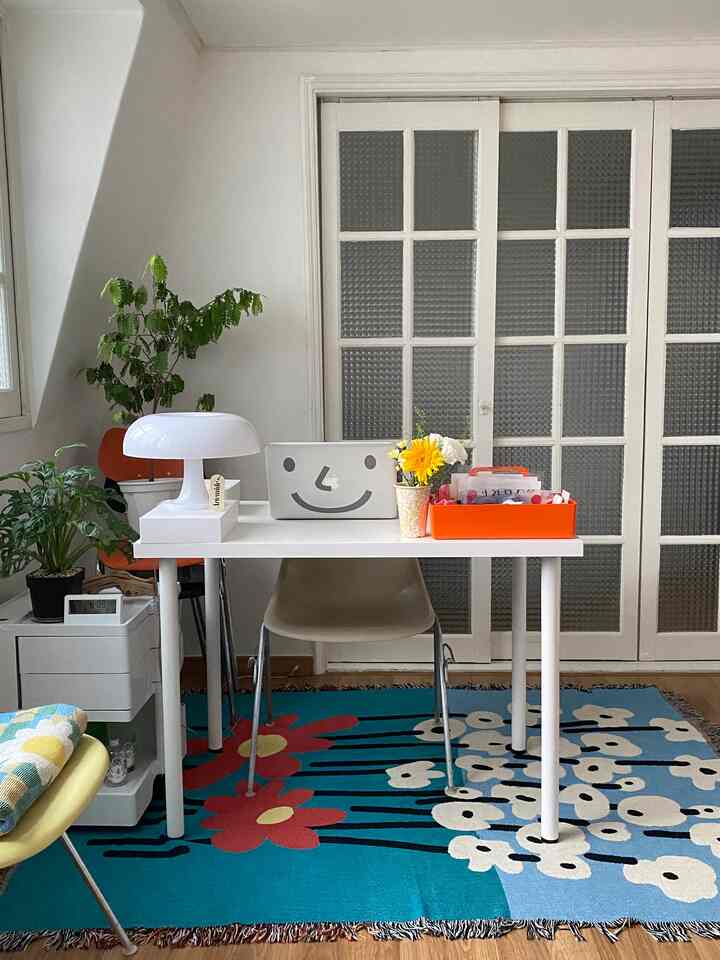 White and natural tone home office space featuring a desk with plants and table lamp, creating a cozy atmosphere