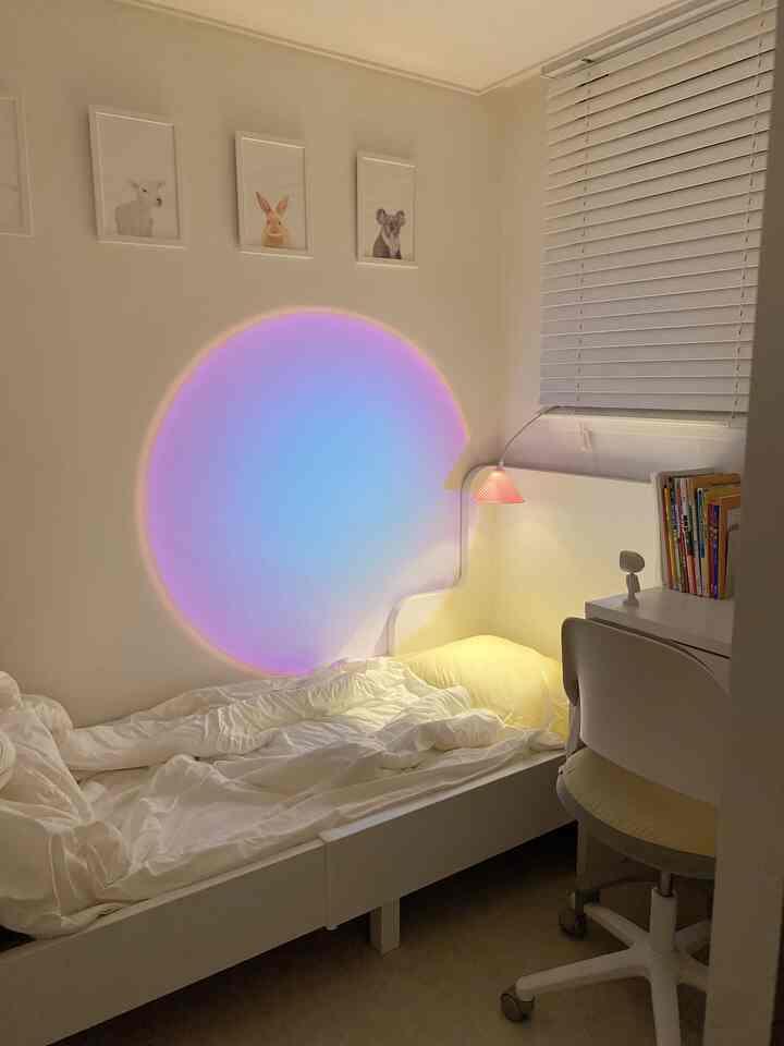 柔らかな白色の子供部屋、清潔な白いベッドとデスク、壁に円形のムードランプが優しく照らす印象的な空間