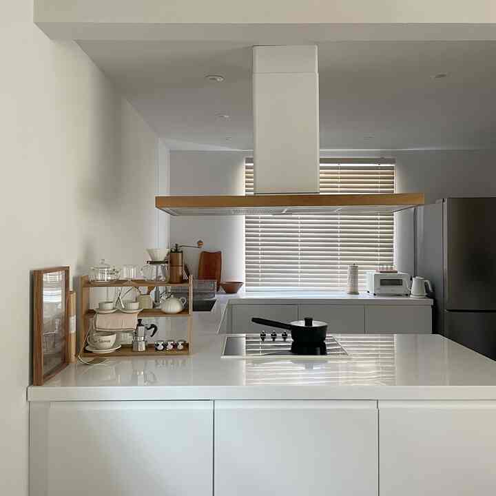 Modern kitchen with white and wood tones, featuring an induction cooktop, wood hood, and kitchen shelves in a cozy setting