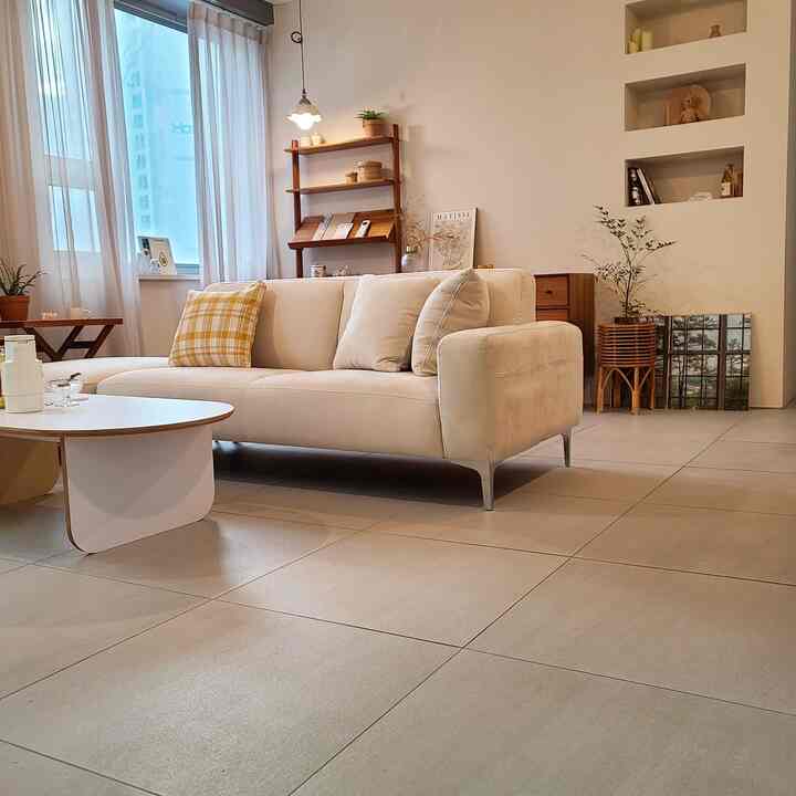 ホワイトとイエローの色調のリビング、ベージュのソファと木製の棚が配置されたシンプルモダンな雰囲気のインテリア