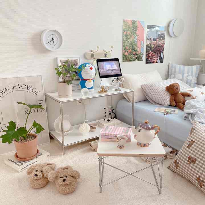 Bright natural modern small bedroom featuring white and light blue bedding, cozy dog slippers, and a teapot on a small table
