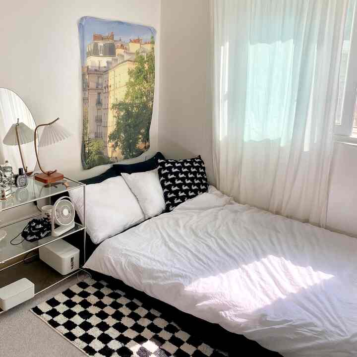 Small bedroom in white and black tones, featuring modern furniture and a checkered rug creating a harmonious space