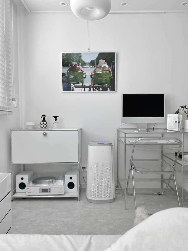 White and silver toned home office space featuring a transparent desk and metal frame furniture with a clean, modern atmosphere