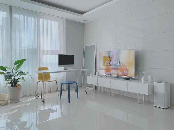 White-toned living room home office with white desk, yellow chair, and plants arranged in a modern interior