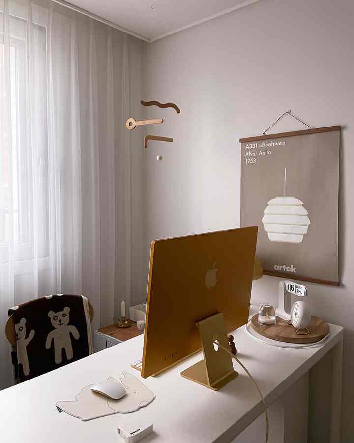Clean home office with white walls and curtains, gold iMac on desk, natural modern style