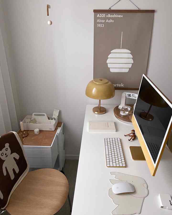 White-walled compact home office featuring a desk with yellow table lamp and computer, creating a calm and orderly atmosphere