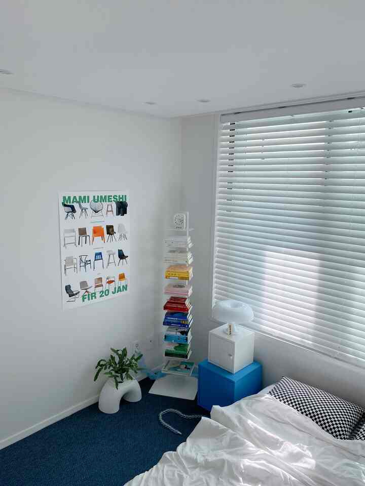Natural white and blue toned 6-tatami bedroom featuring bed with white blinds, poster, bookshelf, and plant creating a clean atmosphere