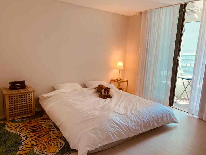 White and beige tone bedroom featuring a large bed and tiger-patterned rug in a simple natural setting