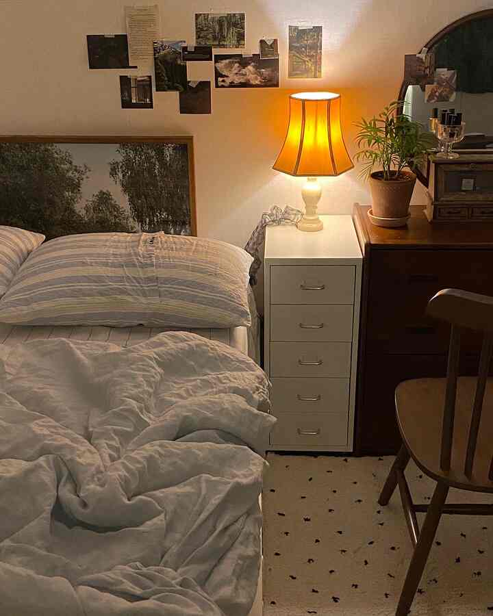 暖かいオレンジ色の照明が灯る寝室、木製家具とポスターが配置された雰囲気のあるヴィンテージスタイルの空間