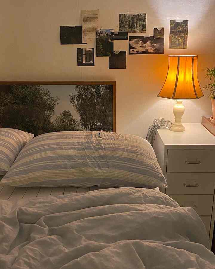 白を基調とした寝室、枕と掛け布団のあるベッド、横に置かれたドレッサーとテーブルランプが雰囲気のある空間