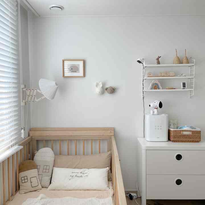 White and beige toned baby room featuring a crib and storage dresser with a clean, natural atmosphere