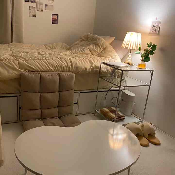 Soft beige-toned bedroom featuring beige bedding, cushioned chair, metal frame desk with lamp creating cozy atmosphere