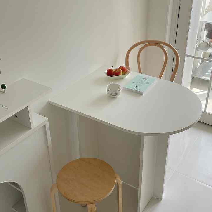 Bright white and natural brown toned dining room featuring a half-oval table with wooden chairs in a cozy arrangement