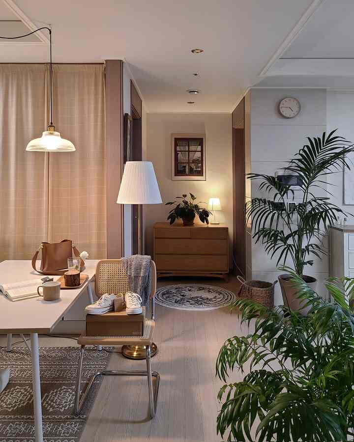 White and beige toned living and dining space featuring wooden furniture and plants with a cozy natural interior