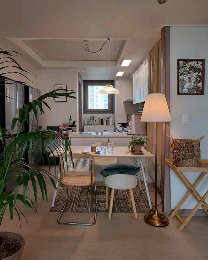 Natural wood-toned dining room for two with plants and kitchen, featuring a cozy and clean atmosphere