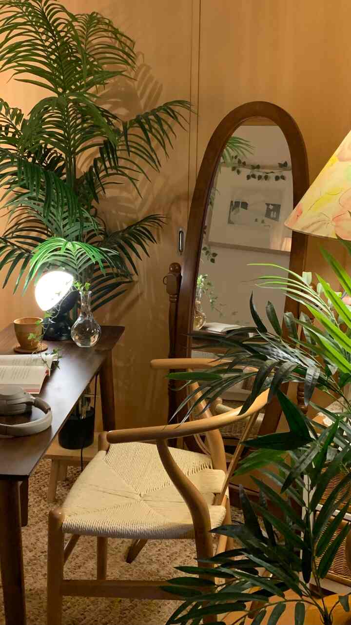 Cozy home office with natural wood tones and green plants, featuring a wooden desk and rattan chair