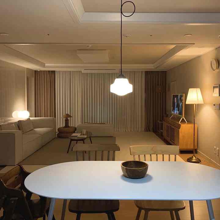 Warm natural-toned living and dining room featuring a cozy sofa, wood tone furniture, and a baby play mat creating a comfortable atmosphere