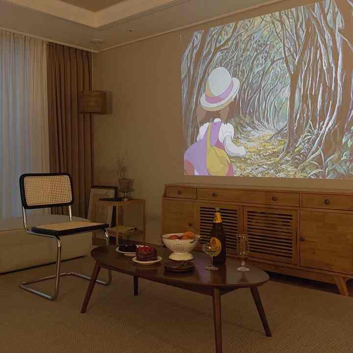 Cozy wood tone cafe-style living room featuring a home cinema setup with a beam projector projecting an animated film