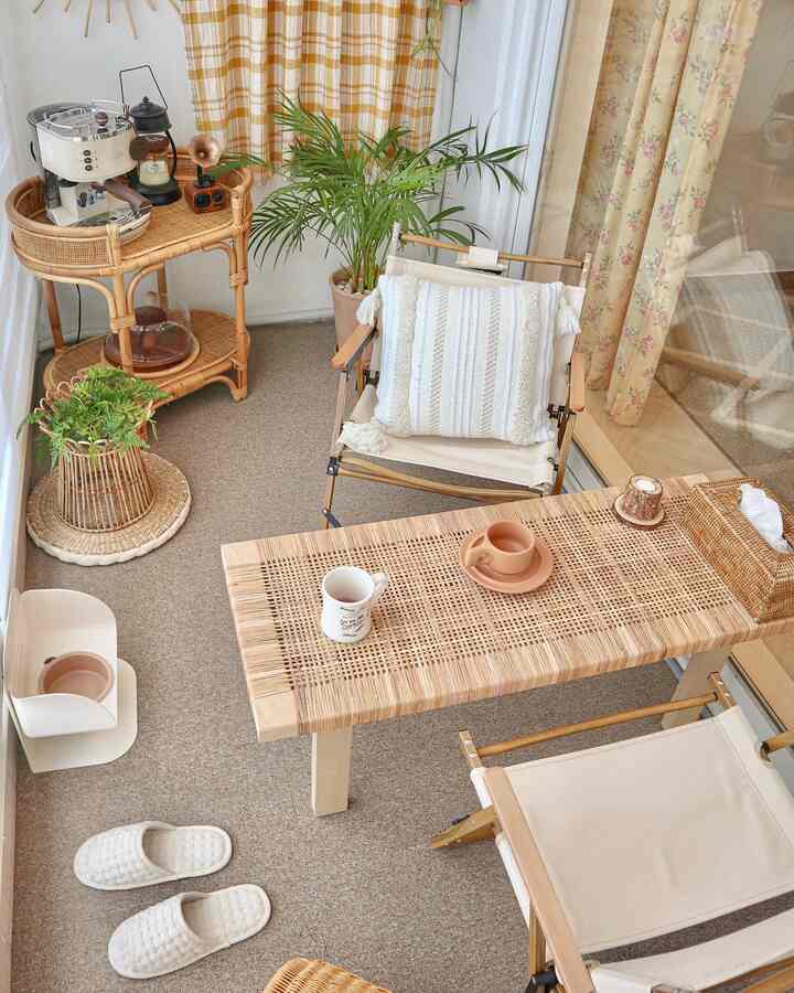 ベージュとナチュラルトーンのベランダ、ラタン家具とホームカフェの要素が配置された雰囲気のある空間