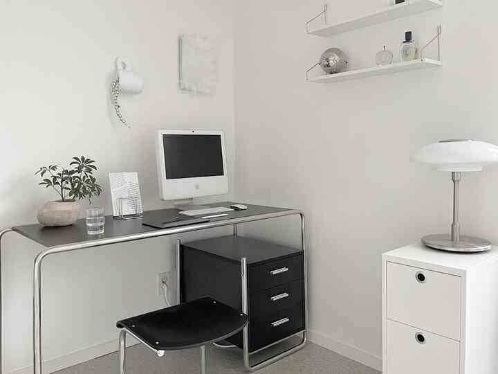 白と黒のミニマルなワンルームホームオフィス、シンプルな机と椅子が配置された清潔感のある空間