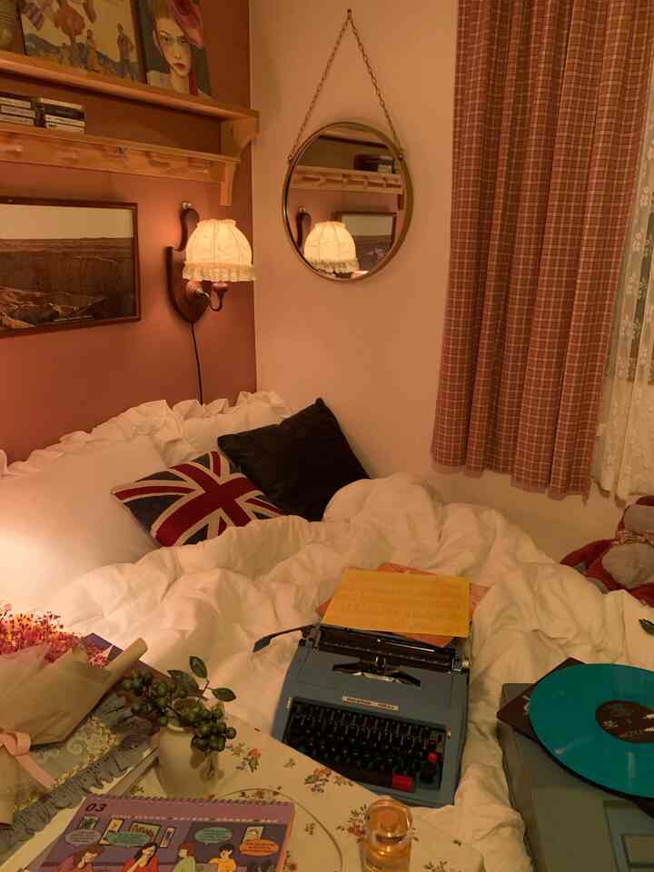 暖かみのあるベージュとブラウンのヴィンテージ風寝室、レースの壁燈と丸い鏡、チェック柄のカーテンと快適なベッドが配置された雰囲気のある空間