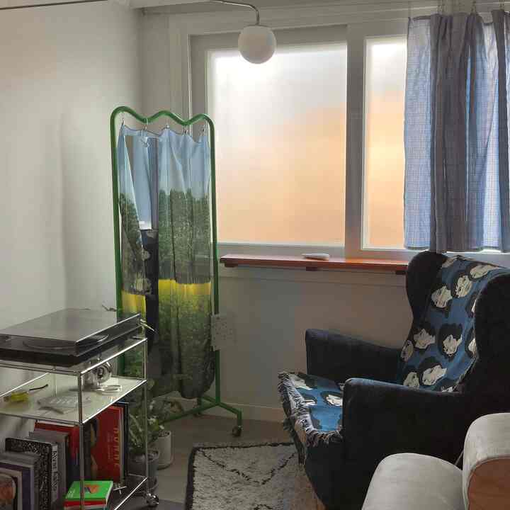 Living room with white walls and blue-toned curtains, featuring an armchair and rug creating a cozy atmosphere
