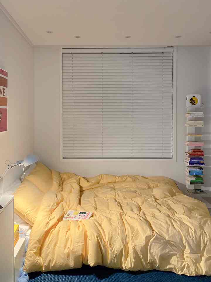 Cozy bedroom featuring yellow bedding and white blinds with minimal decor