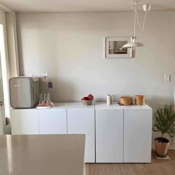 ホワイトと木目調が調和したキッチンスペース、シンプルなキャビネットが配置され清潔感のある印象的な空間