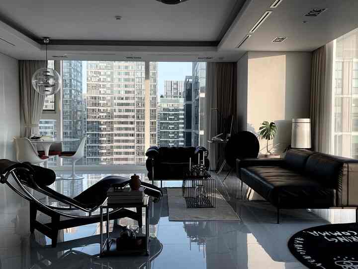 Modern living room with prominent black furniture, large windows, and white curtains creating a bright and sleek atmosphere
