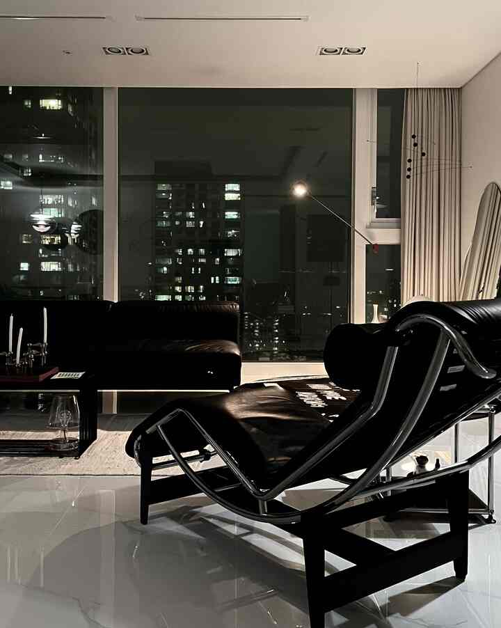 ダークなブラックトーンのミッドセンチュリーモダンなリビング、黒いレザ―ソファとラウンジチェアが配置された洗練された空間