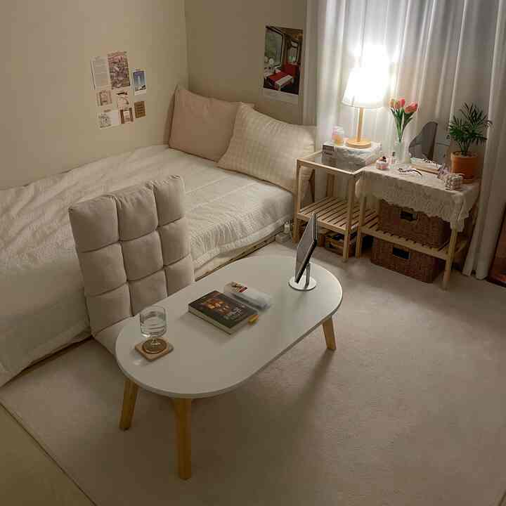 ベージュとアイボリーの色調でまとめられた、ローテーブルとクッションチェアが配置された、暖かい照明と植物がある印象的な寝室のインテリア