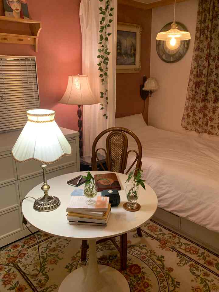 Cozy bedroom in light brown and white tones featuring a round dining table and vintage lamps creating a warm atmosphere