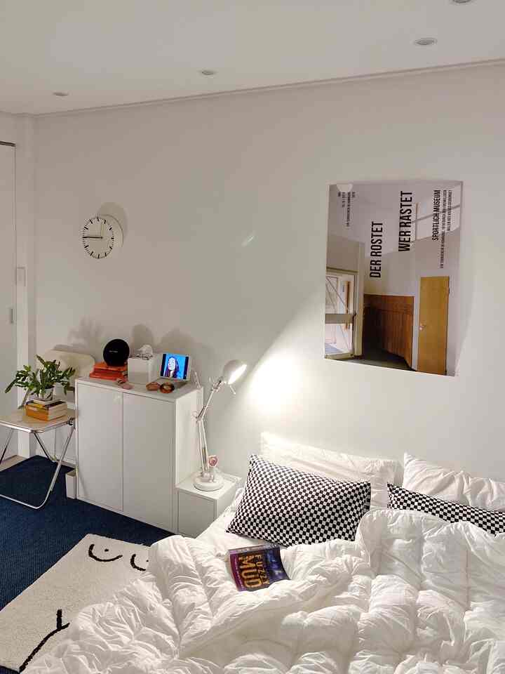 白を基調とした寝室、整った寝具とチェック柄の枕が配置された雰囲気のある空間