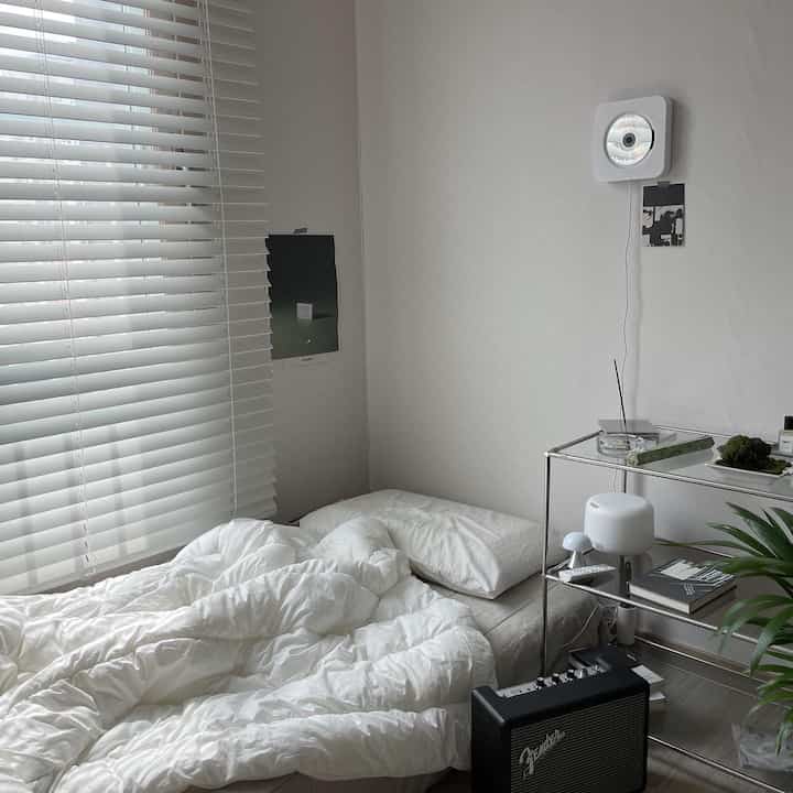 White-toned bedroom featuring white blinds and bedding with a simple, natural atmosphere